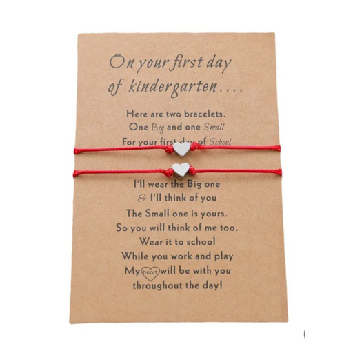 Set of red string bracelets with heart charms on a message card
