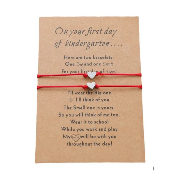 Set of red string bracelets with heart charms on a message card