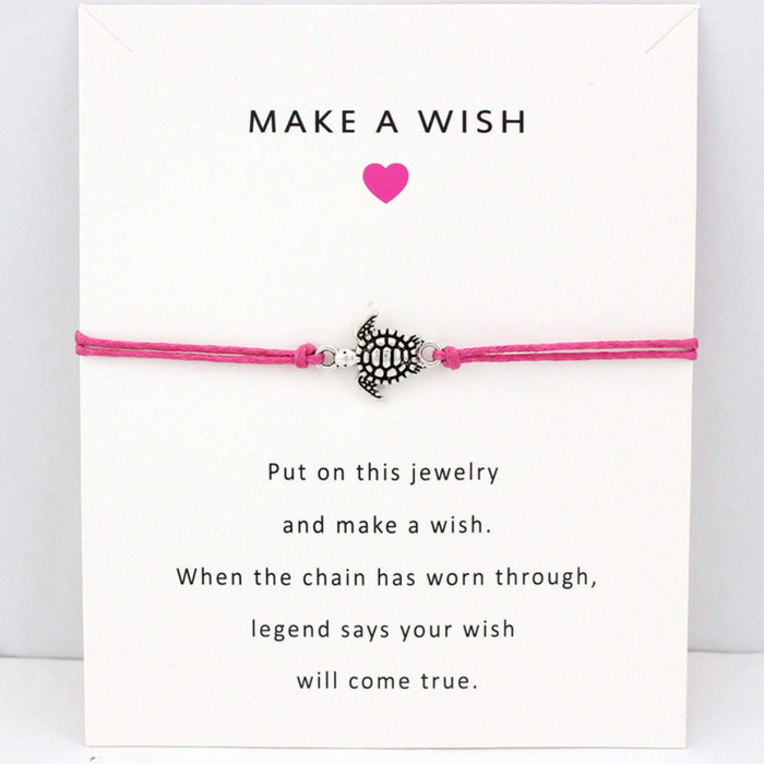 Pink string bracelet with turtle charm on a white message card