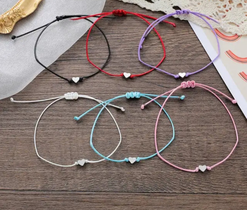 Different colour bracelets with heart charms on a table