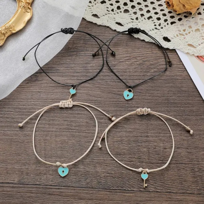 Black and beige bracelets with lock and key charms on a table 