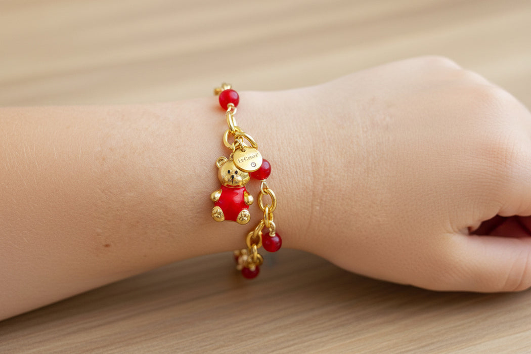 girl wearing gold bracelet with red bear charm