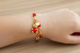 girl wearing gold bracelet with red bear charm